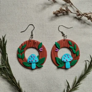 Handgemachte Ohrringe aus Polymer Clay mit türkisfarbenen Pilzen, grünen Blättern und lilafarbenen Beeren auf brauner Holzstruktur, inspiriert von einem Waldmotiv